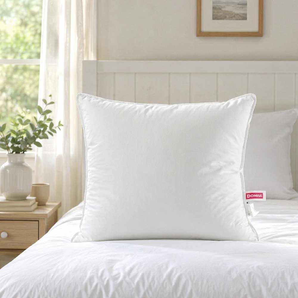 Perna Serene puf gasca 80x80 asezata pe pat alb cu decor de plante