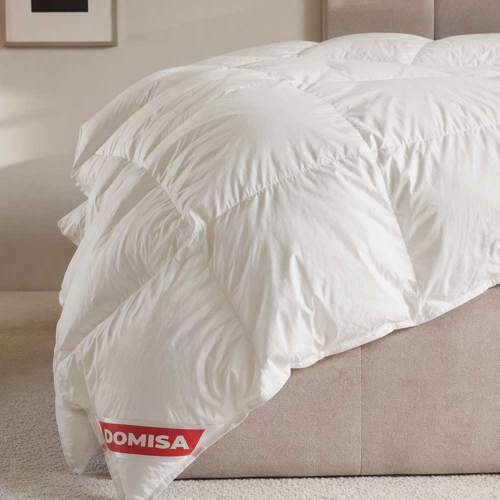 Pilotă albă Ovia 200x220 cm din puf și pene de gâscă, așezată pe pat, cu aspect pufos și confortabil.