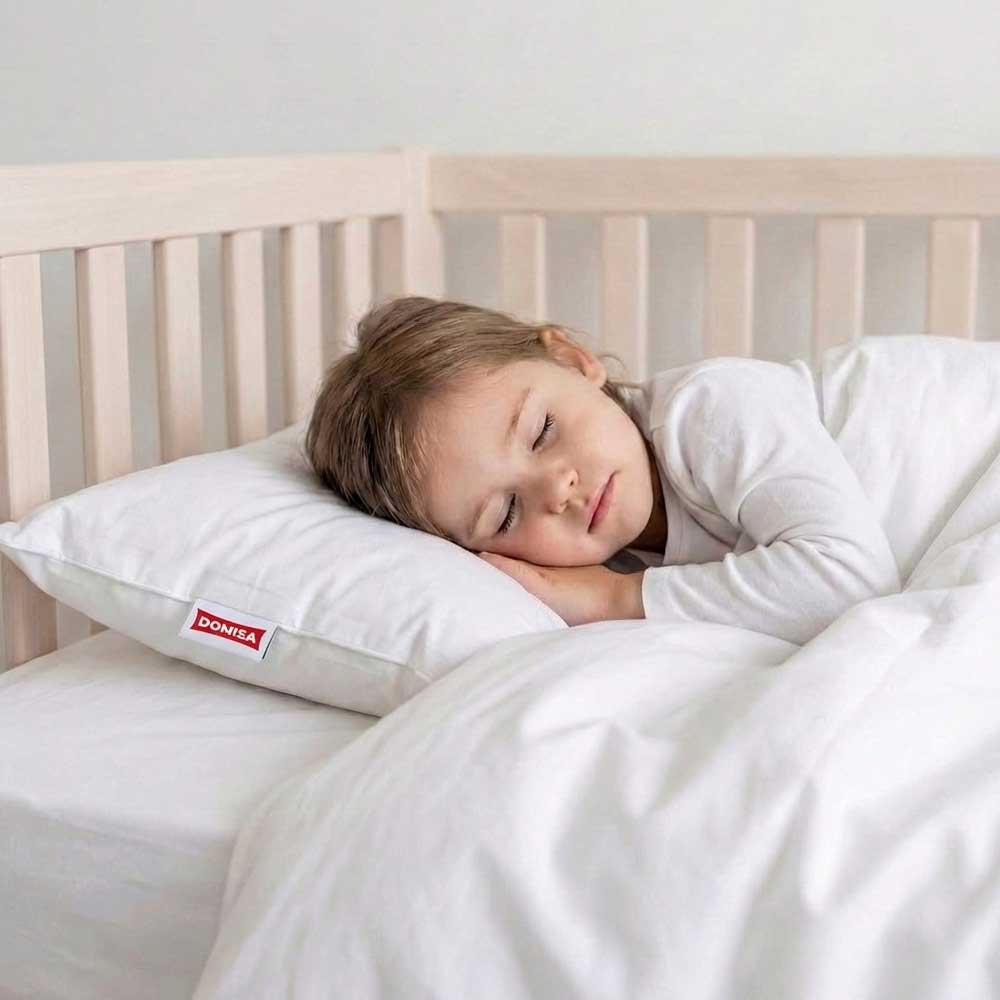 Perna de copii 30x50cm din puf si pene de gasca asezata sub capul unei fetite care doarme