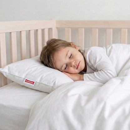 Perna de copii 30x50cm din puf si pene de gasca asezata sub capul unei fetite care doarme