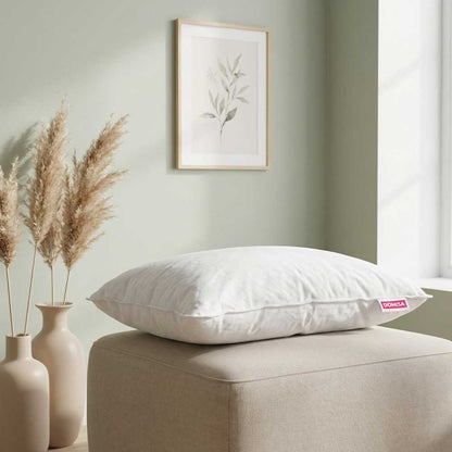 Perna Ovia cu pene de gasca 50x70 asezata pe un taburete intr-o camera moderna