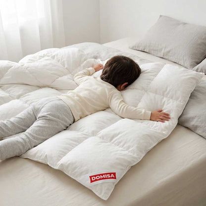 Pilota de copii naturala din puf de gasca 100x140 cm alba cu un copil intins pe ea